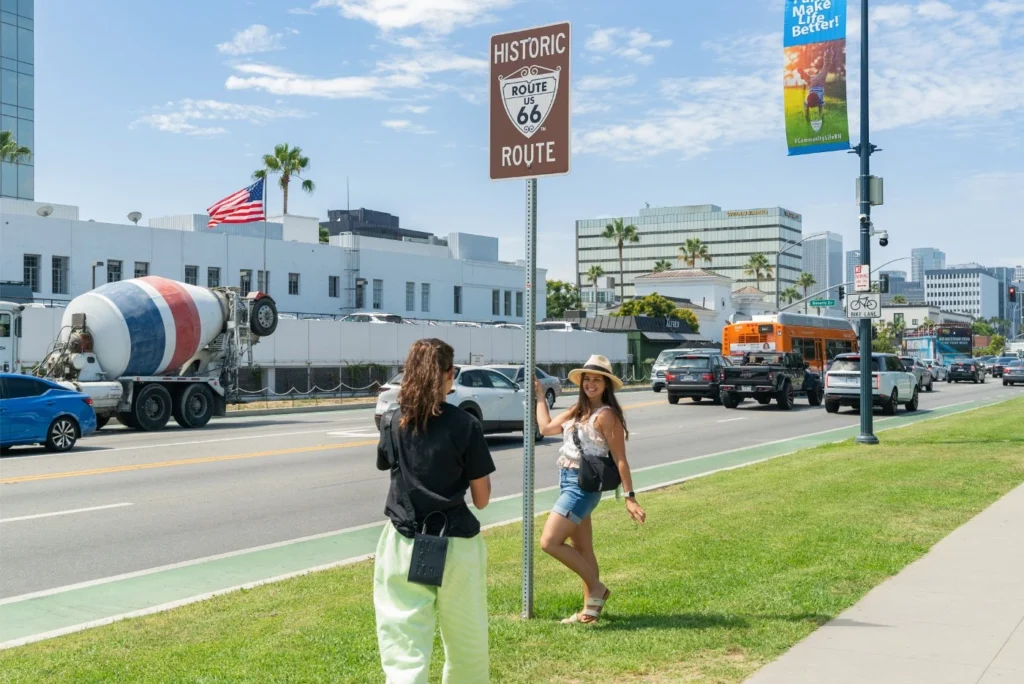 tourist posing near historic Route 66 sign in Beverly Hills