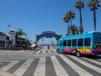 Santa Monica Pier entrance sign with Hollywood tour bus nearby