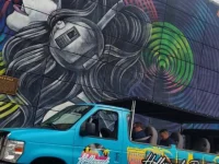 Hollywood Bus Tours van driving past colorful Los Angeles street mural