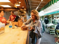 visitor buying food at a stall inside Original Farmers Market Los Angeles