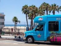Hollywood Bus Tours vehicle near Santa Monica beach and palm trees