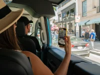 tourist filming Rodeo Drive luxury shops from tour bus