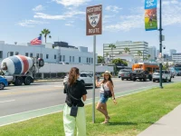 tourists posing at historic Route 66 sign in Beverly Hills