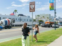 tourist posing near historic Route 66 sign in Beverly Hills