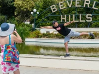 tourist posing at Beverly Hills sign fountain landmark