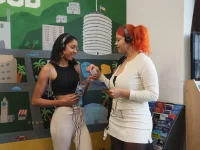 Tour guests wearing headphones reviewing a Hollywood Bus Tours brochure inside a Los Angeles attraction.