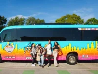 tourists posing beside Hollywood Bus Tours sightseeing bus