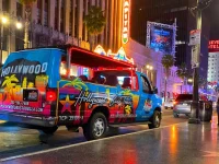 Hollywood Bus Tours vehicle driving along Hollywood Boulevard at night