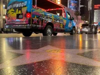 Hollywood Bus Tours van parked on Hollywood Walk of Fame with neon lights