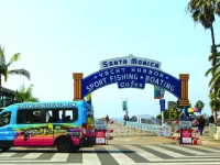 Hollywood Bus Tours van parked at Santa Monica Pier sign entrance