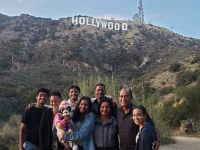 family taking photo with Hollywood sign in background Los Angeles